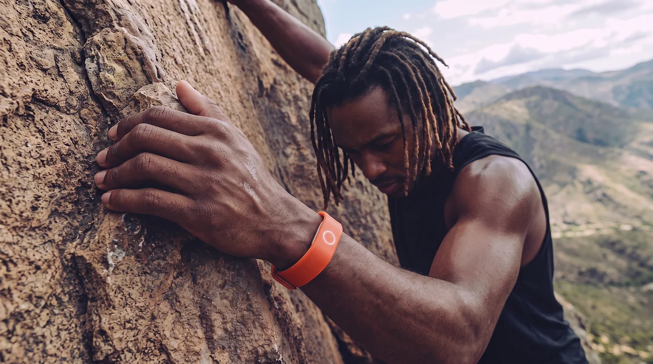 A climber wearing Persona Band, Liquid in Capri Orange